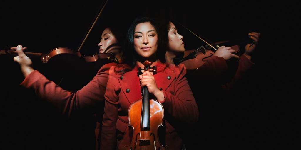 Jennifer Trijo holds a violin and is positioned in the shot three times, facing to the front and to both sides with a black background and dramatic lighting